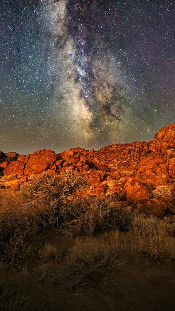 Night sky stars over red orange mountains desert
