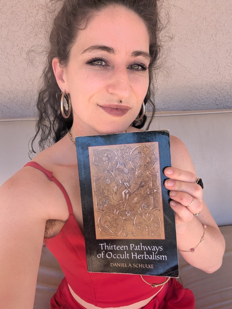 A photo of Raphael holding the book Thirteen Pathways of Occult Herbalism