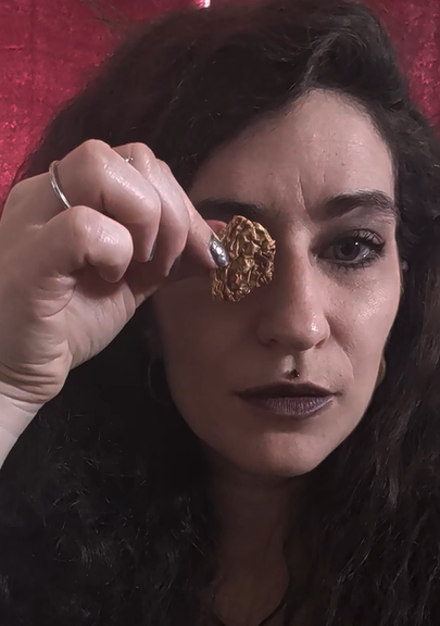 Raphael holding a small piece of Amanita mushroom over their eye