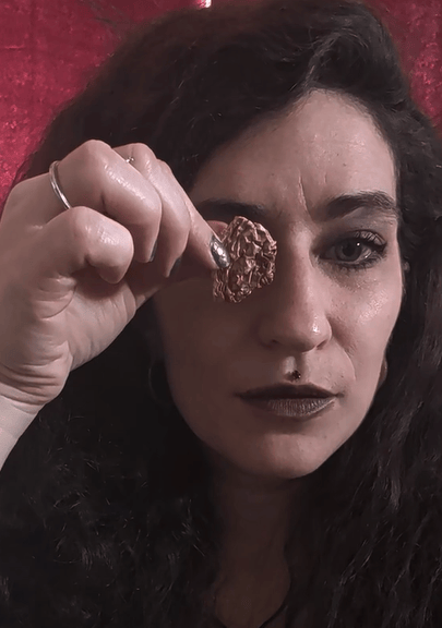 Raphael holding a small piece of Amanita mushroom over their eye